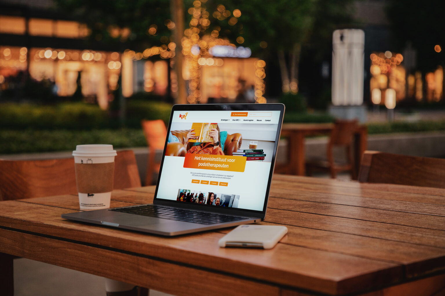 laptop op een tafel van een terras met daarop een beeld van de website van Kipz