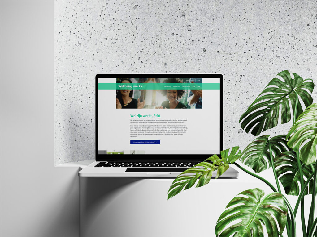 Laptop met website van Wellbeing works naast een plant